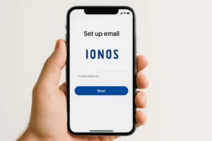 La main tient un smartphone sur lequel s'affiche la configuration d'une messagerie Ionos pour iOS